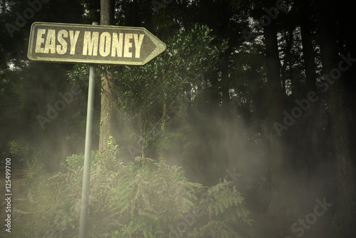 Fotografi old signboard with text easy money near the sinister forest