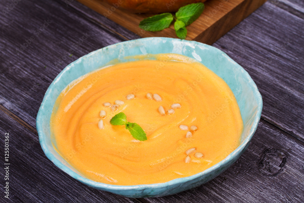Bowl of pumpkin soup and  whole pumpkin. Butternut squash cream soup