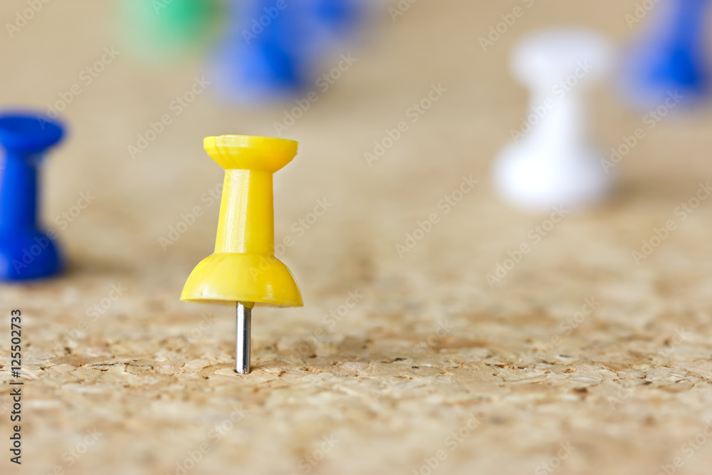 Closeup image of a yellow pushpin on a cork board. Closeup image of a yellow pushpin on a cork board.