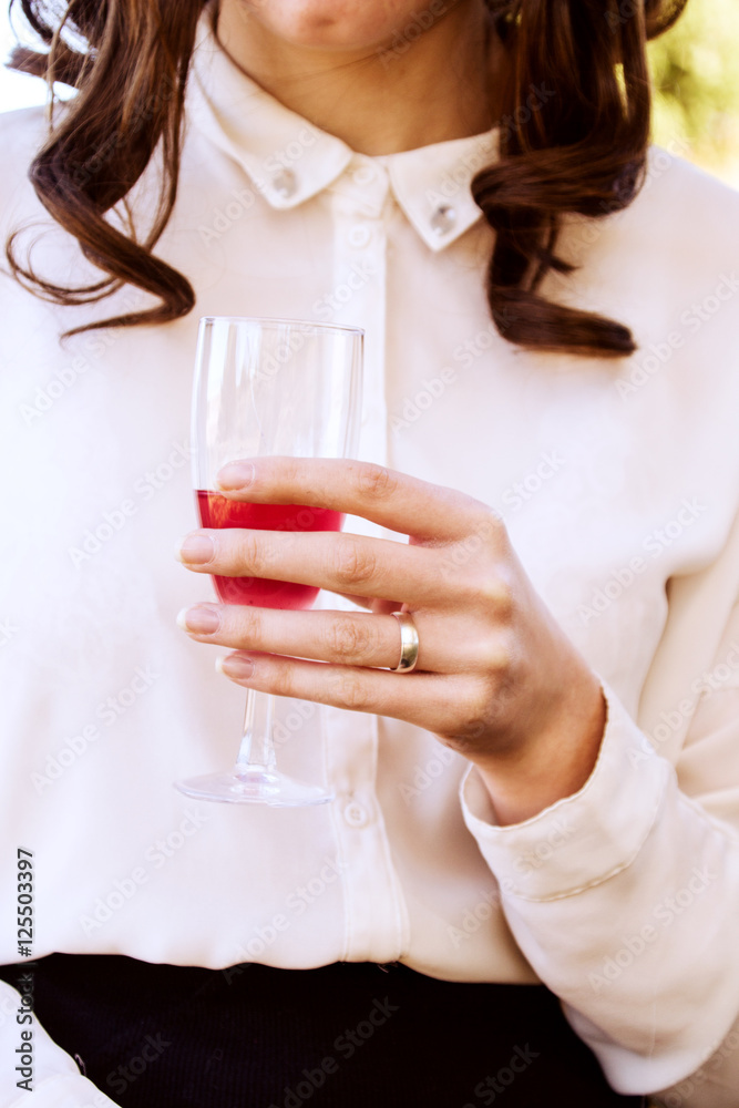 Mujer joven sosteniendo una copa de vino con la mano en la que lleva su anillo de compromiso Mujer joven sosteniendo una copa de vino con la mano en la que lleva su anillo de compromiso