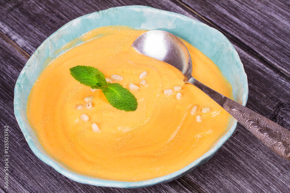 Bowl of pumpkin soup and whole pumpkin. Butternut squash cream soup Bowl of pumpkin soup and whole pumpkin. Butternut squash cream soup