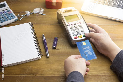 Cashier hand made a payment with Credit card and EDC machine or credit card terminal with calculator and glasses. Warm toning effect.