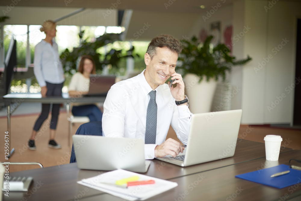 Financial professional man making call and using laptop