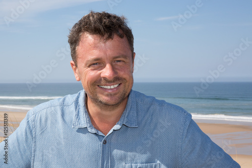 Cheerful smiling mature male model wearing blue shirt in summer scenery