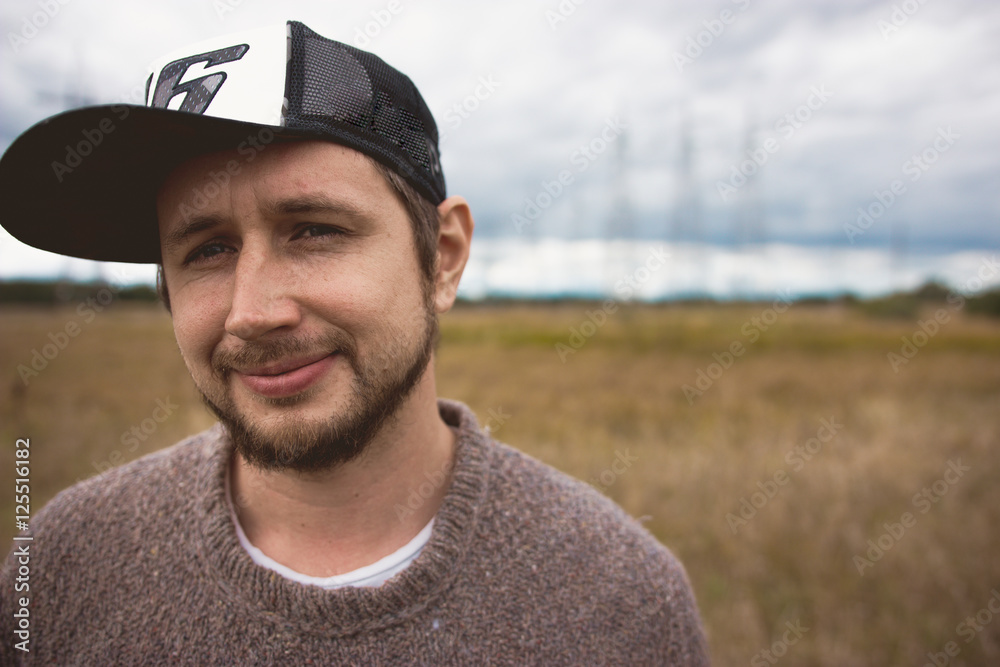 Portrait of adult courageous young man on meadow, power pylons at background Portrait of adult courageous young man on meadow, power pylons at background