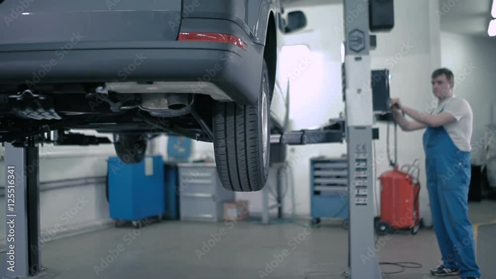 Man puts the car on the lift to the floor. Man puts the car on the lift to the floor.