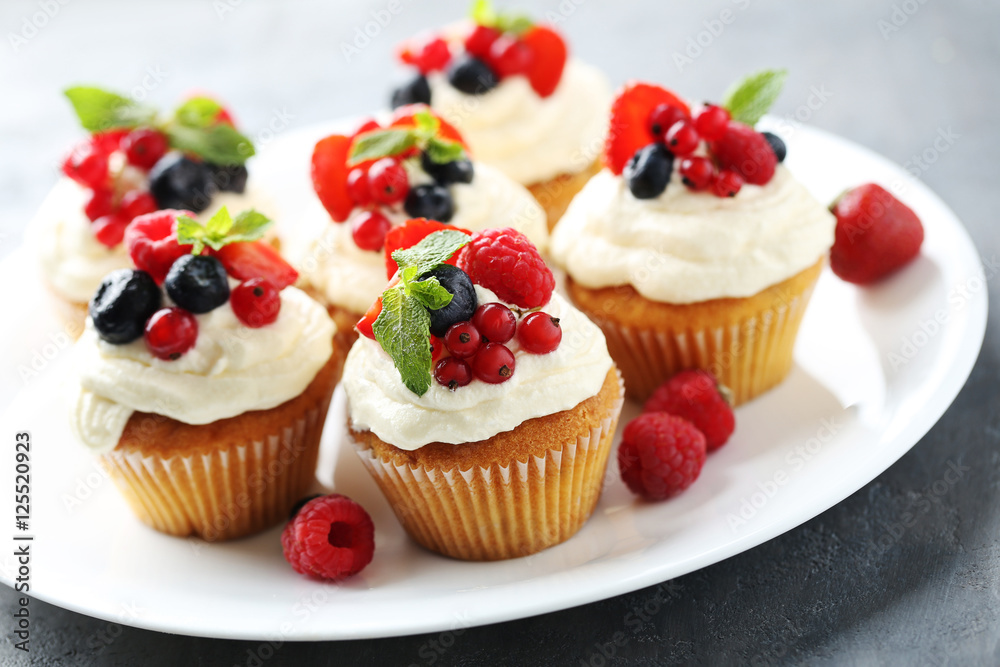 Tasty cupcakes with berries on grey table