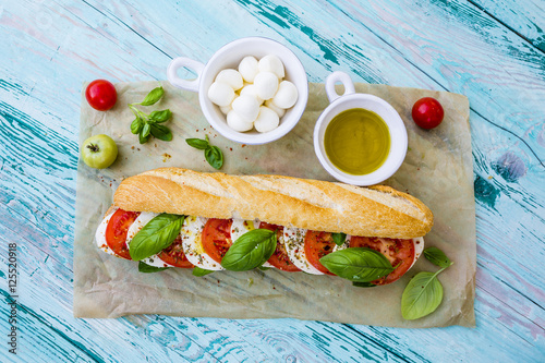 Delicious sandwich with caprese salad with ripe tomatoes and mozzarella cheese with fresh basil leaves. Italian food. 