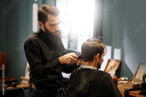 Barber man cutting a client's hair clippers in the barbershop