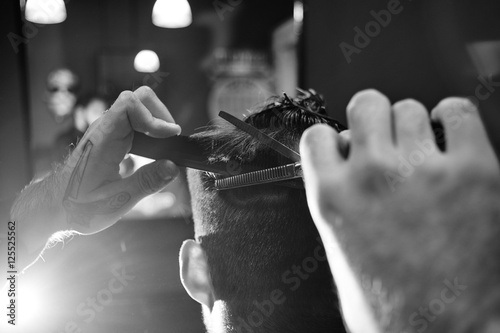 Hand cut with scissors human hair in Barbershop, closeup black-and-white photo