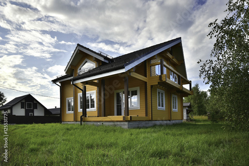 wooden house on green grass with blue sky