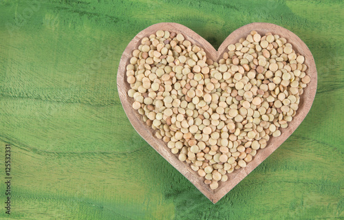 Raw lentils in the wooden bowl shaped heart