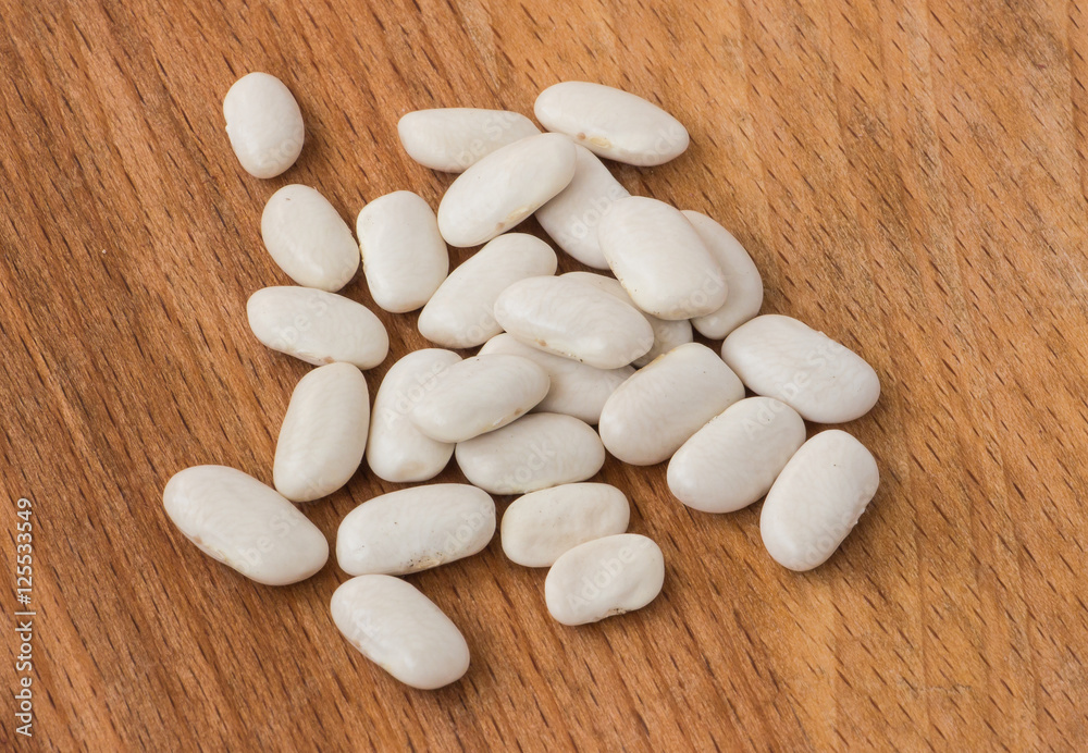 White beans closeup on a wooden background.