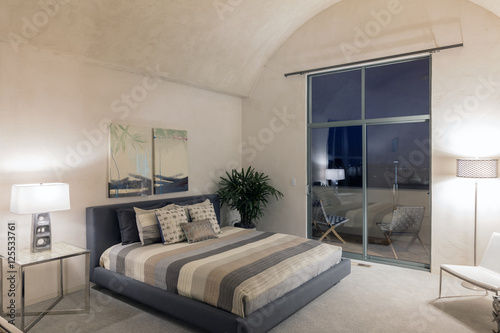 Modern luxurious bedroom with a balcony at night.