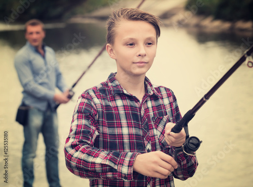 Positive boy casting line for fishing on lake