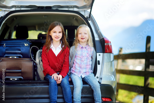 Two adorable little sitting in a car before going on vacations with their parents