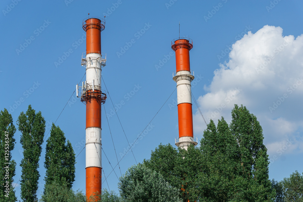 Red and white factory pipes in the cloudy sky Red and white factory pipes in the cloudy sky