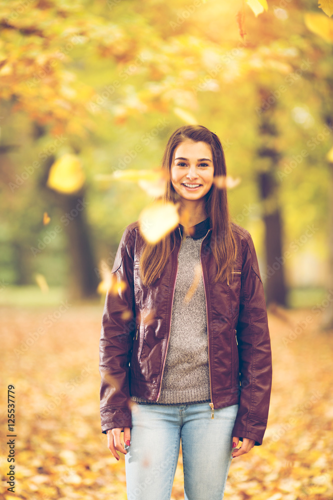 Young girl is having fun with falling leaves in a park Young girl is having fun with falling leaves in a park
