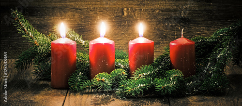 Dritter Advent: drei leuchtende Kerzen vor einem Holzhintergund