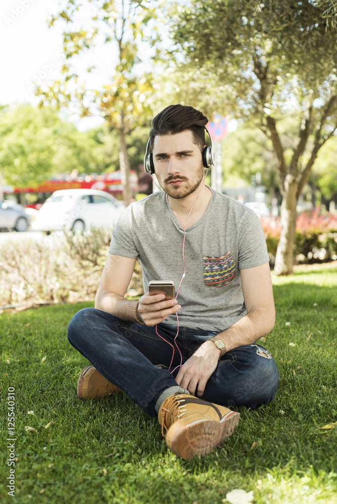 Young man using a smart phone and listening to the music with headphones