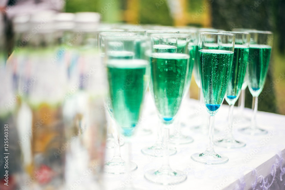 A lot of wine glasses with a cool delicious champagne or white wine at the bar. Blue Alcohol background. A lot of wine glasses with a cool delicious champagne or white wine at the bar. Blue Alcohol background.