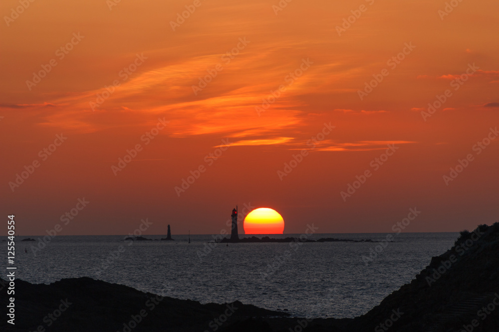Burning sunset in ocean with a lighthouse