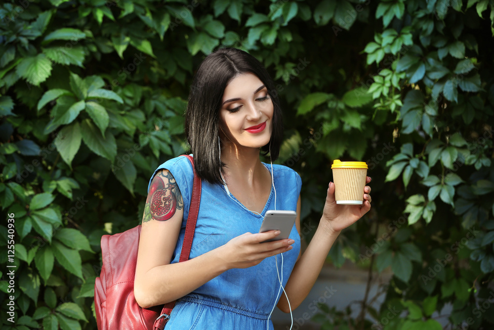 Young beautiful girl outdoors with phone and cup of coffee Young beautiful girl outdoors with phone and cup of coffee