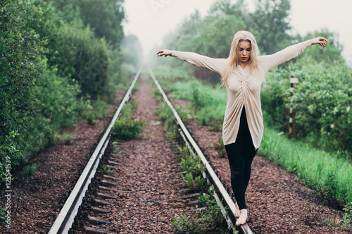 Portrait of young girl walking on rails in motion with hands on opposite directions