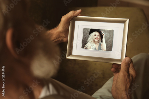 Elderly man holding photo f...