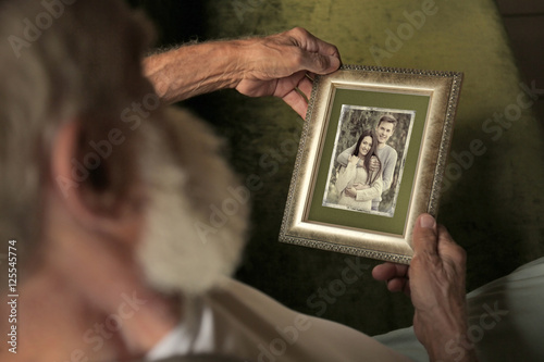 Elderly man holding photo f...