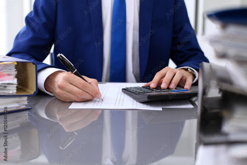 Close up view of bookkeeper or financial inspector hands making report, calculating or checking balance. Internal Revenue Service inspector checking financial document. Close up view of bookkeeper or financial inspector hands making report, calculating or checking balance. Internal Revenue Service inspector checking financial document.