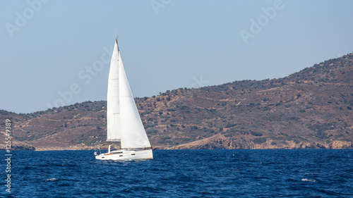 Sailing ship luxury yacht with white sails near the Greek coast.