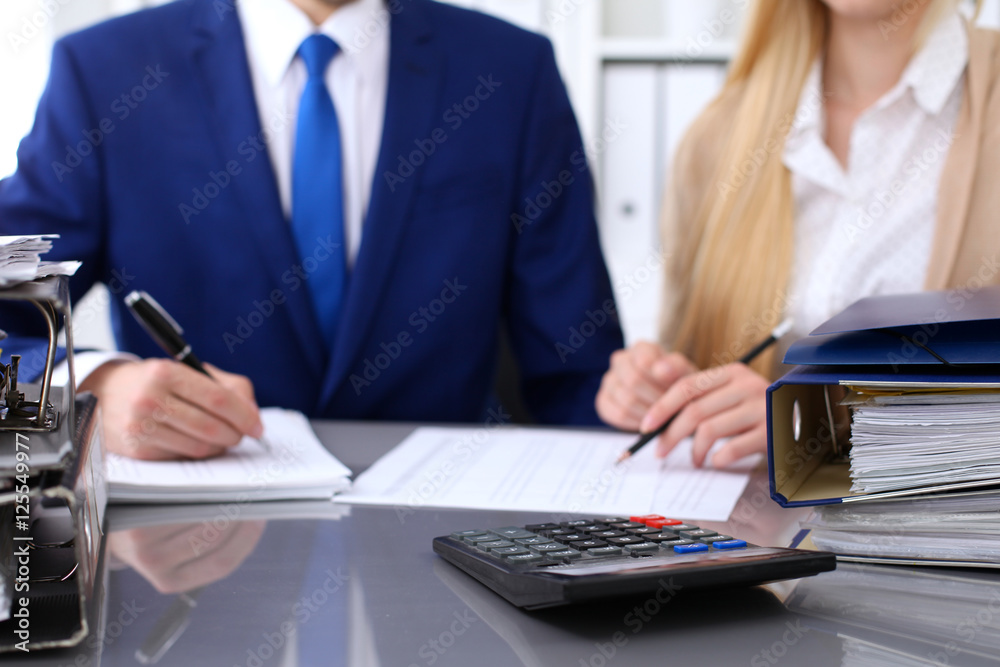 Bookkeeper or financial inspector and secretary making report, calculating or checking balance. Internal Revenue Service inspector checking financial document. Audit concept. Bookkeeper or financial inspector and secretary making report, calculating or checking balance. Internal Revenue Service inspector checking financial document. Audit concept.