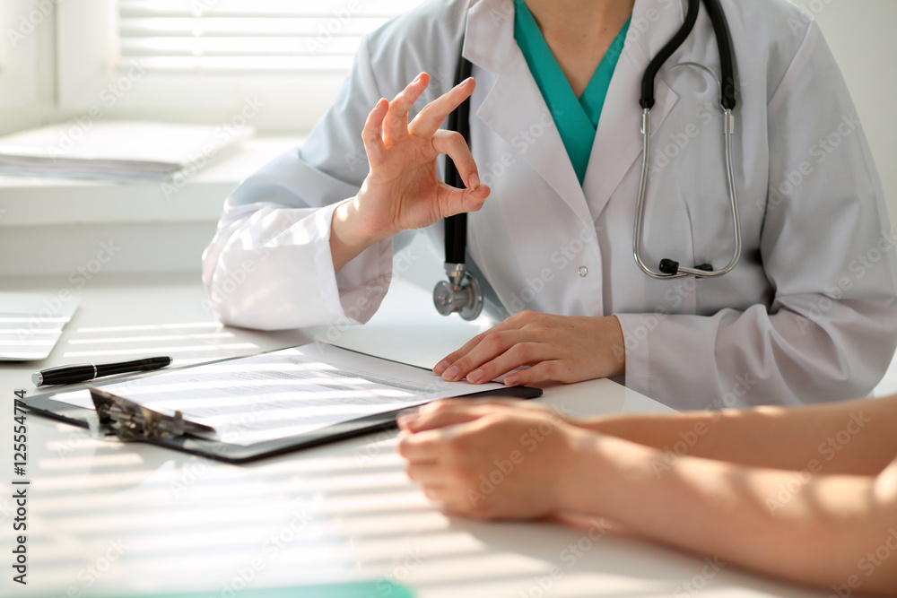 Hand of doctor reassuring her female patient and showing ok sign. Medical ethics and trust concept Hand of doctor reassuring her female patient and showing ok sign. Medical ethics and trust concept
