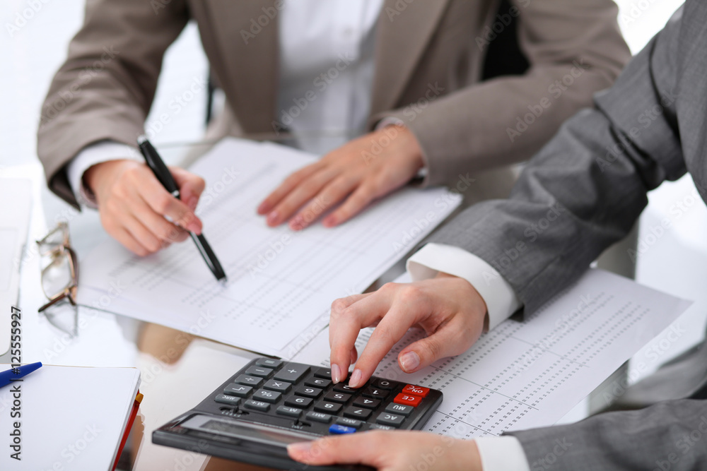 Two female accountants counting on calculator income for tax form completion hands closeup. Internal Revenue Service inspector checking financial document. Planning budget, audit concept Two female accountants counting on calculator income for tax form completion hands closeup. Internal Revenue Service inspector checking financial document. Planning budget, audit concept