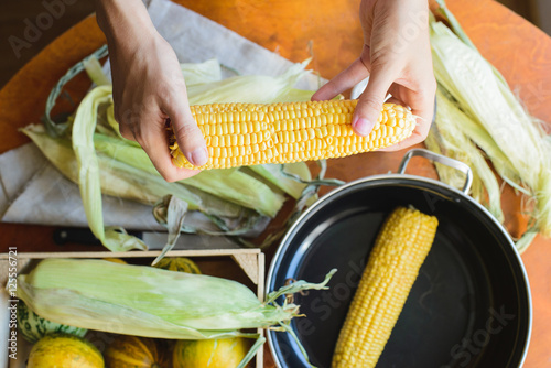top view of woman prepares corn for cooking in bowl