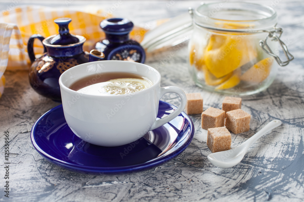 tea with a lemon in a cup, a teapot and sugar on a table, selective focus tea with a lemon in a cup, a teapot and sugar on a table, selective focus