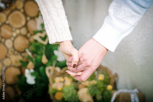 Two hands held together on the background of a winter home comfort. Love together, men's and women's hands with a house in winter evening 