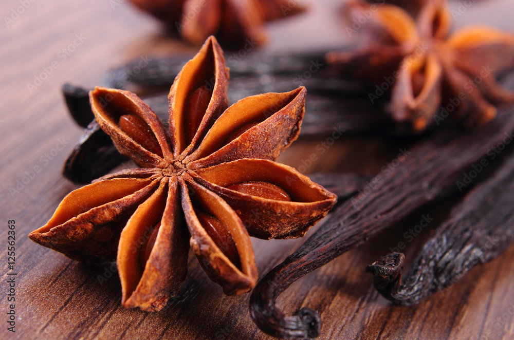 Closeup of star anise and fragrant vanilla on wooden surface plank