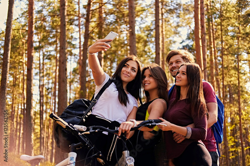 Three smiling girls and one guy making selfie after bicycle ride