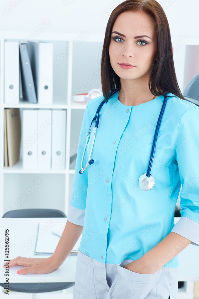 Beautiful female medicine doctor Beautiful female medicine doctor standing rests her hand on the table in her office. Medical help or insurance concept. Beautiful female medicine doctor Beautiful female medicine doctor standing rests her hand on the table in her office. Medical help or insurance concept.