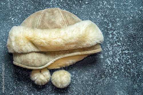 Women's winter hat leather and fur on a dark cement background