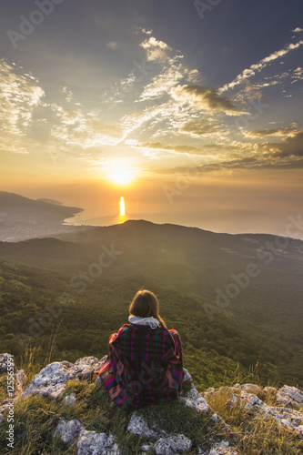 Canvas Print sitting girl in yellow sunrise in mountains above sea
