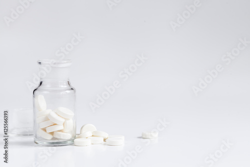 pills in glass jar on white background