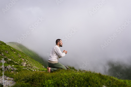 praying man on fog dark sky background