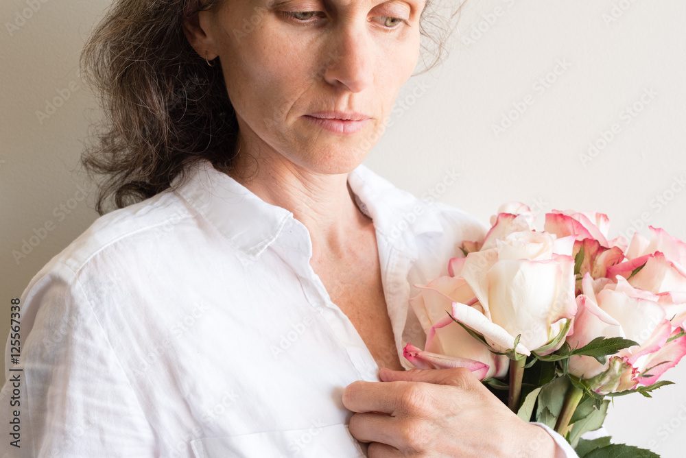 Middle aged woman holding roses and looking pensive (cropped) Middle aged woman holding roses and looking pensive (cropped)