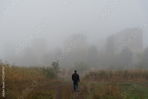 man walking to a town in fog