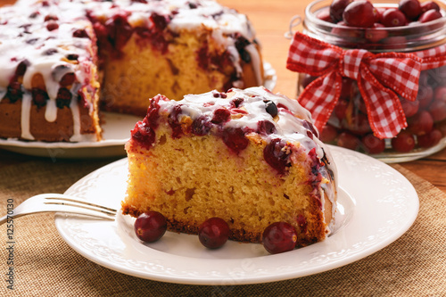 Cranberry cake with icing on brown wooden background. photo