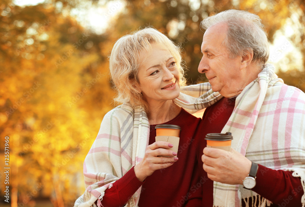 Lovely mature couple with coffee in autumn park Lovely mature couple with coffee in autumn park