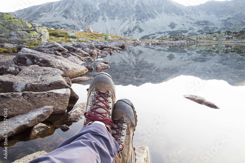 Hiking.Woman legs with boots and mountain lake view
